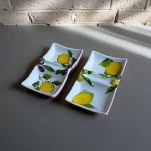 details of a white ceramic appetizer tray decorated with lemons and olives on a white background