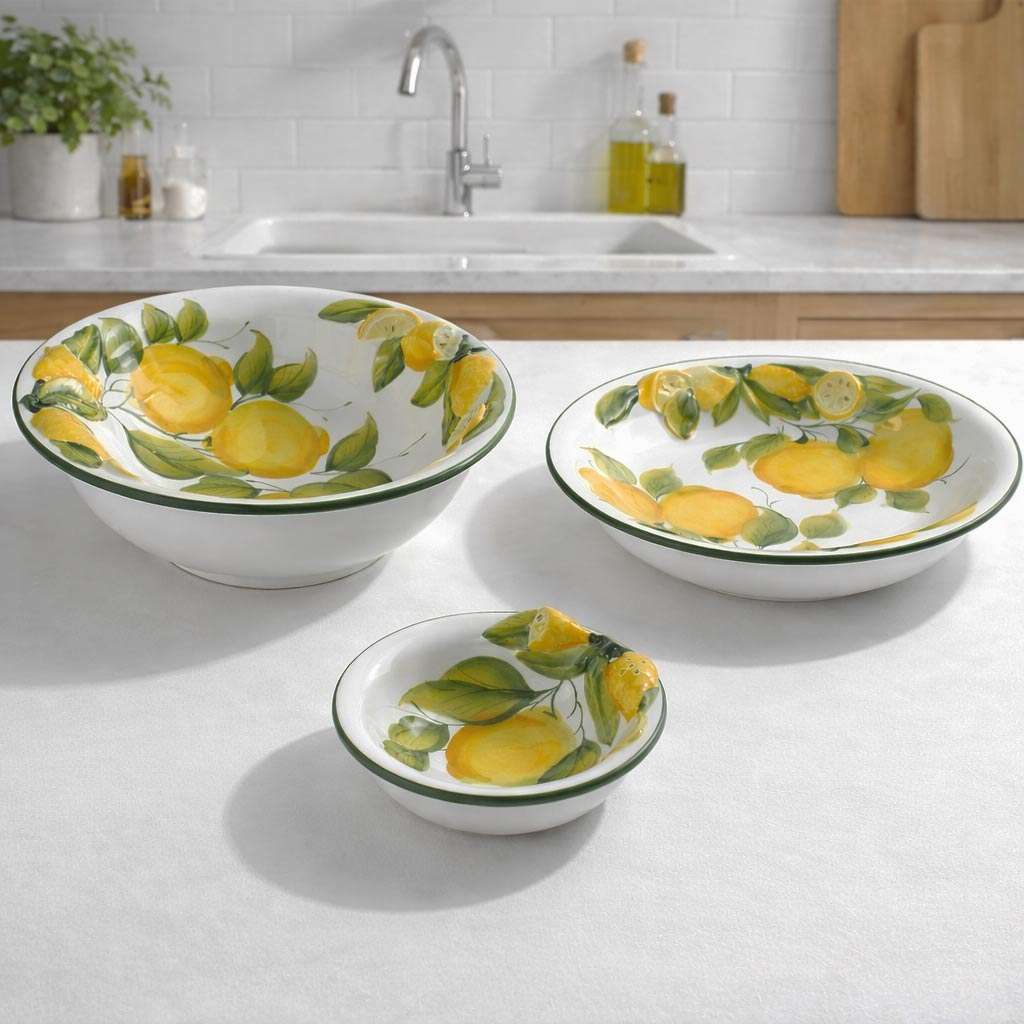 Ceramic serving set consisting of a central bowl, a small bowl, and a plate, featuring a lemon and leaf design on a white background.<br/>.