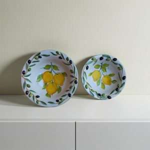 Handcrafted ceramic bowl decorated with lemon and olive motifs on a white background