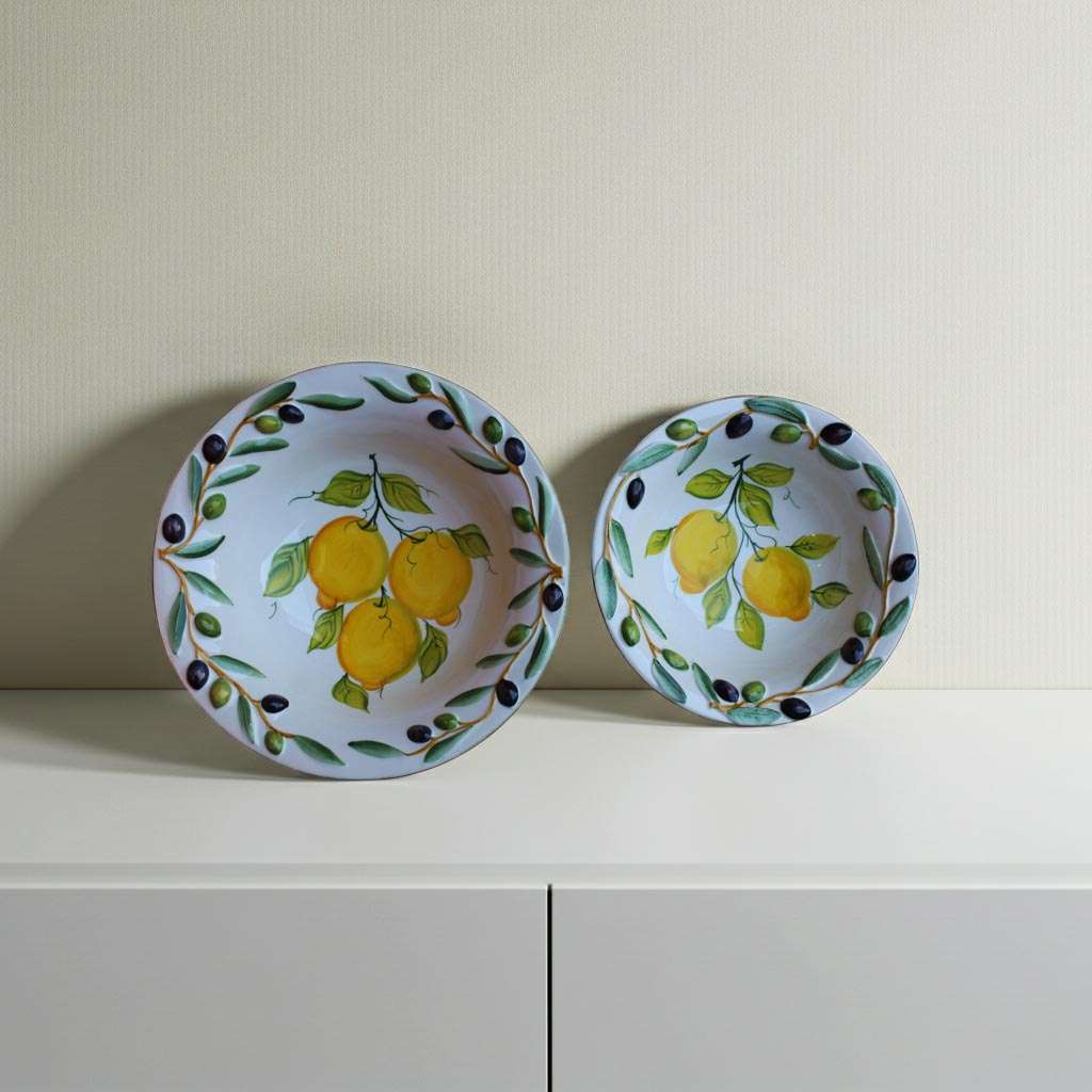 Handcrafted ceramic bowl decorated with lemon and olive motifs on a white background