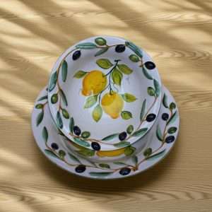 Handcrafted ceramic bowl decorated with lemon and olive motifs on a white background