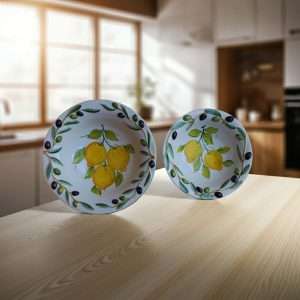 Details of handcrafted ceramic bowl decorated with lemon and olive motifs on a white background
