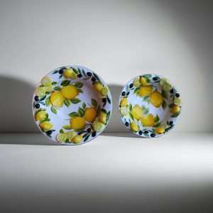 ceramic bowl decorated with lemons and olives on a white background