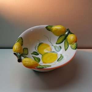 dettagli di bolo in ceramica con manici decorato in limoni e foglie su sfondo bianco