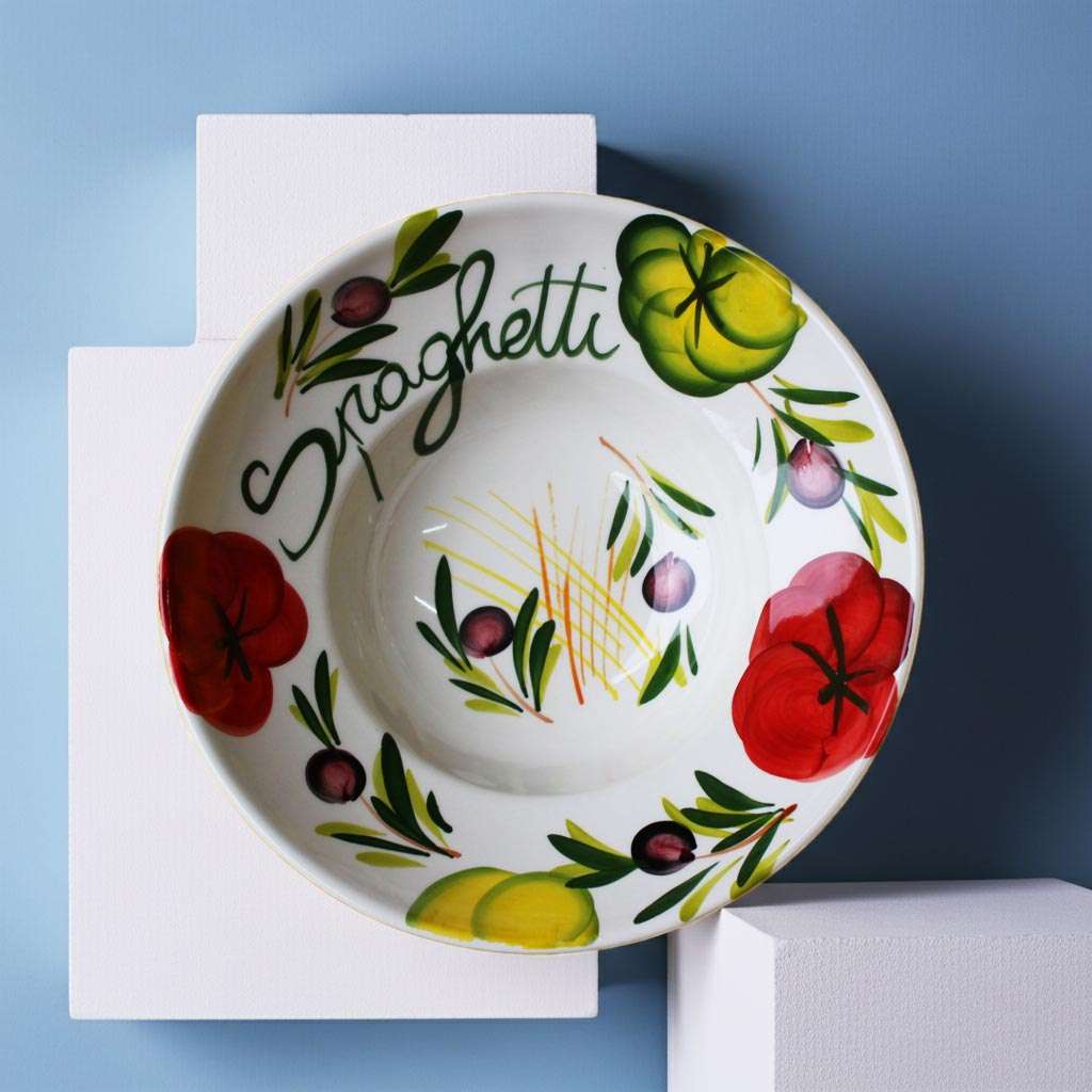 hand-decorated priest's hat plate with tomatoes and olives on white background