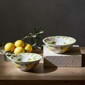 dettagli di bolo e ciotola in ceramica con decoro limone e oliva su sfondo bianco