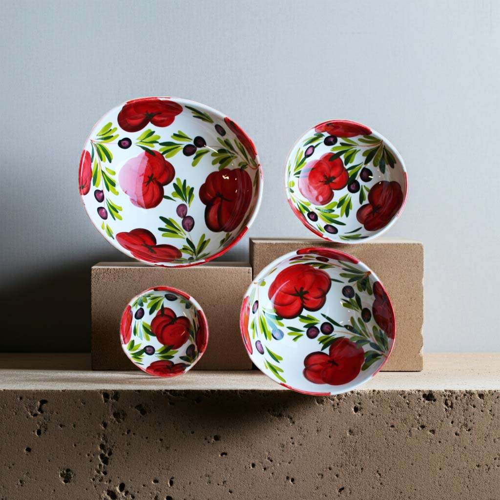 Italian ceramic bowls in various sizes decorated with tomato and olive design on a white background