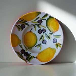 dettagli di piatto cappello da prete decorato con limoni e olive su sfondo bianco