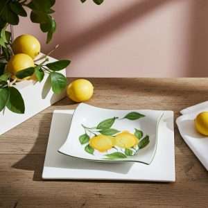 Top view of ceramic plate, bowl, and salad bowl set with lemon and leaf design on white background