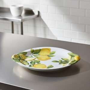 dettagli di piatto per dolce e piatto piano artigianale con decoro limone e foglie su sfondo bianco
