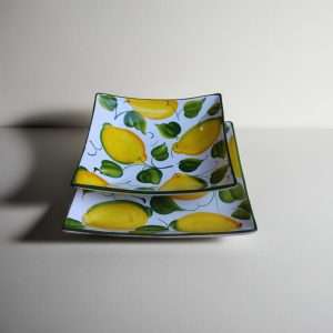 details of square ceramic plates featuring a lemon and leaf design on a white background.