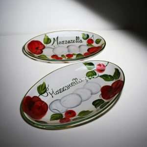 dettagli di pirofile in ceramica decorate con pomodoro e mozzarella su sfondo bianco