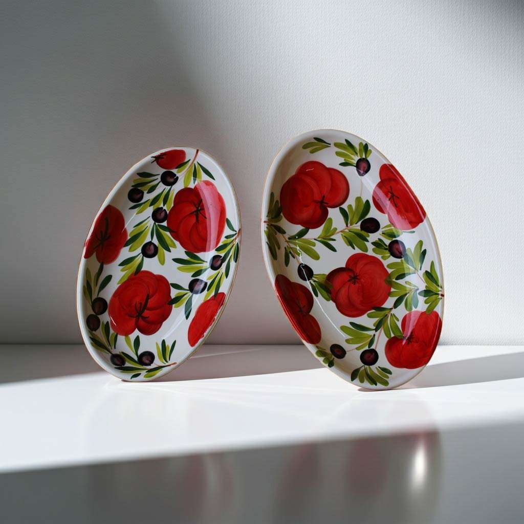 Ceramic baking dishes with tomato and olive decoration on white background