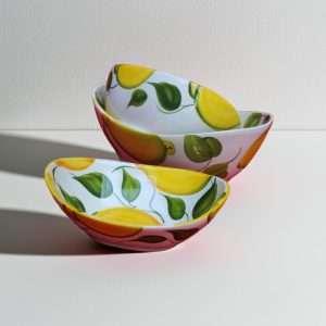 handmade ceramic bowl decorated with lemons and leaves on a white background