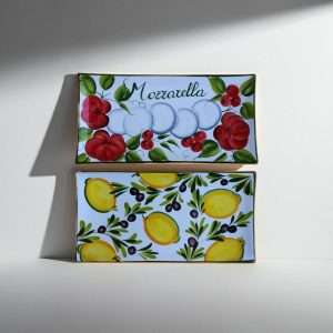 Details of a white ceramic tray with lemon, olive, tomato, and mozzarella decorations on a white background.