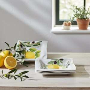 square white ceramic plate decorated with lemons, leaves, and olives on a white background