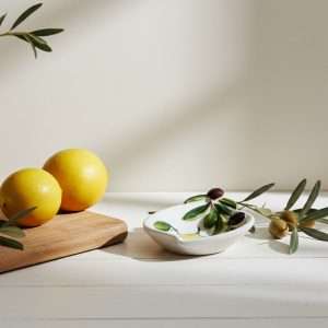 ceramic sauce boat in two designs: lemon, and lemon with olive on a white background