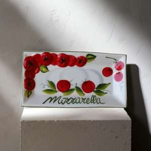 details of small ceramic tray with embossed tomato and mozzarella decorations on a white background