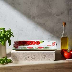 Small ceramic tray decorated in relief with tomatoes and mozzarella on a white background.