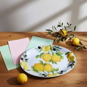 Details of set of decorated ceramic trays with lemon and olive motifs on a white background