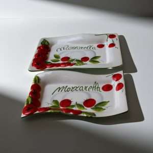 details of hand-decorated tray with embossed tomato decorations and mozzarella details on a white background
