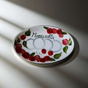 details of Italian handcrafted white tray decorated with tomato and mozzarella design on a white background