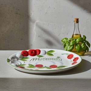 dettagli di vassoio made in Italy in ceramica con rilievo, decorato a mano con pomodoro e mozzarella su sfondo bianco