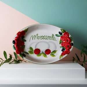 handcrafted ceramic tray with embossed tomato decorations and a central mozzarella design on a white background