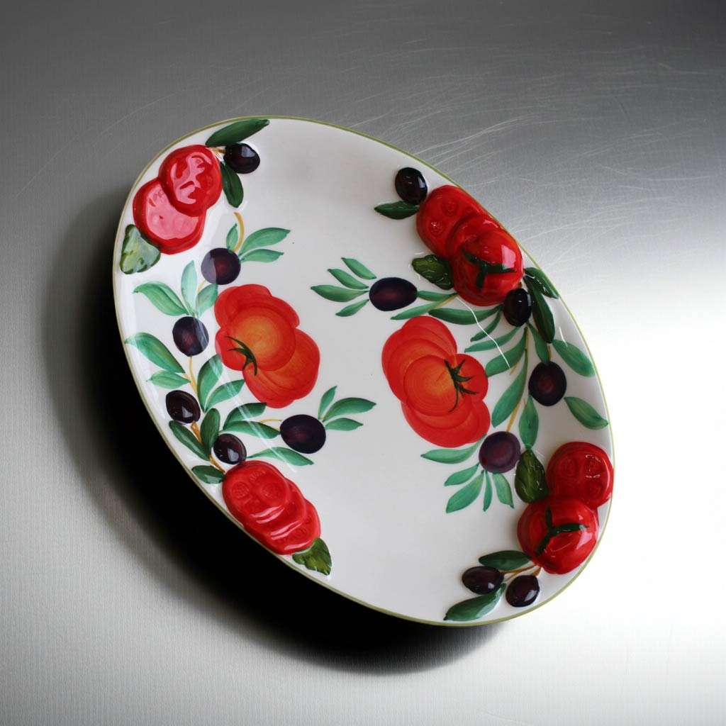details of the handcrafted ceramic tray, hand-decorated with tomato and olive design on a white background.